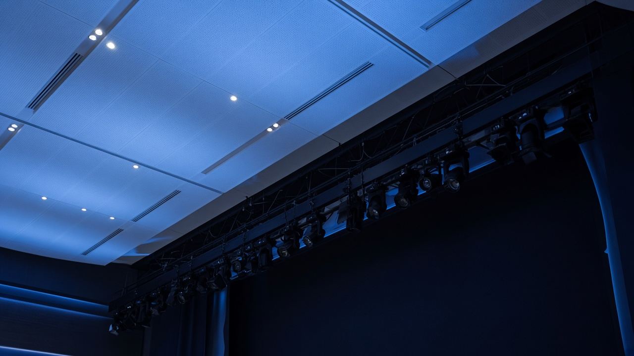 Architectural light over a dark stage